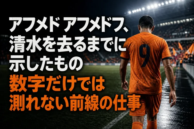 スタジアムを背にピッチを歩くオレンジのユニフォームを着たサッカー選手。