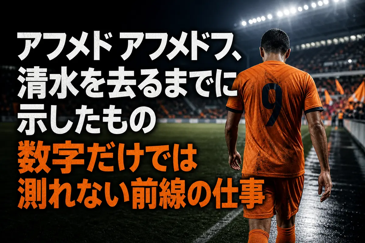 スタジアムを背にピッチを歩くオレンジのユニフォームを着たサッカー選手。