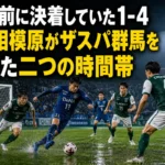 雨上がりのスタジアムで攻防を繰り広げるサッカー選手たち。