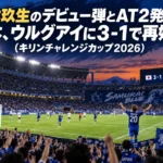 満員のスタジアムで青いユニホームの選手が得点を喜ぶ夜の試合風景