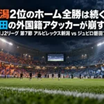 ナイターのスタジアムでキックオフを待つ観客席とピッチの様子。