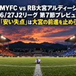 藤枝MYFC vs RB大宮アルディージャ|2026/27J2リーグ 第7節プレビュー:藤枝の「安い失点」は大宮の前進を止められるか ナイター照明に照らされたサッカースタジアムのピッチとセンターサークルに置かれたボール