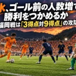夕暮れのスタジアムで紺色の守備陣に攻め込むオレンジ色の選手たちのイメージ。