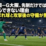 照明に照らされたサッカー場でゴール前の攻防に備える選手たち。