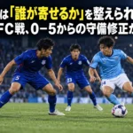 夜のサッカー場でボール保持者に寄せる守備者と、その背後をカバーする選手のイメージ。
