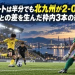 シュートは半分でも北九州が2-0――高知との差を生んだ枠内3本の結末 海辺のスタジアムでゴールを狙う選手と守備陣を描いたサッカーのイラスト。