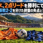 緑の丘に囲まれたサッカー場を背景に並ぶオレンジと青のユニフォーム。